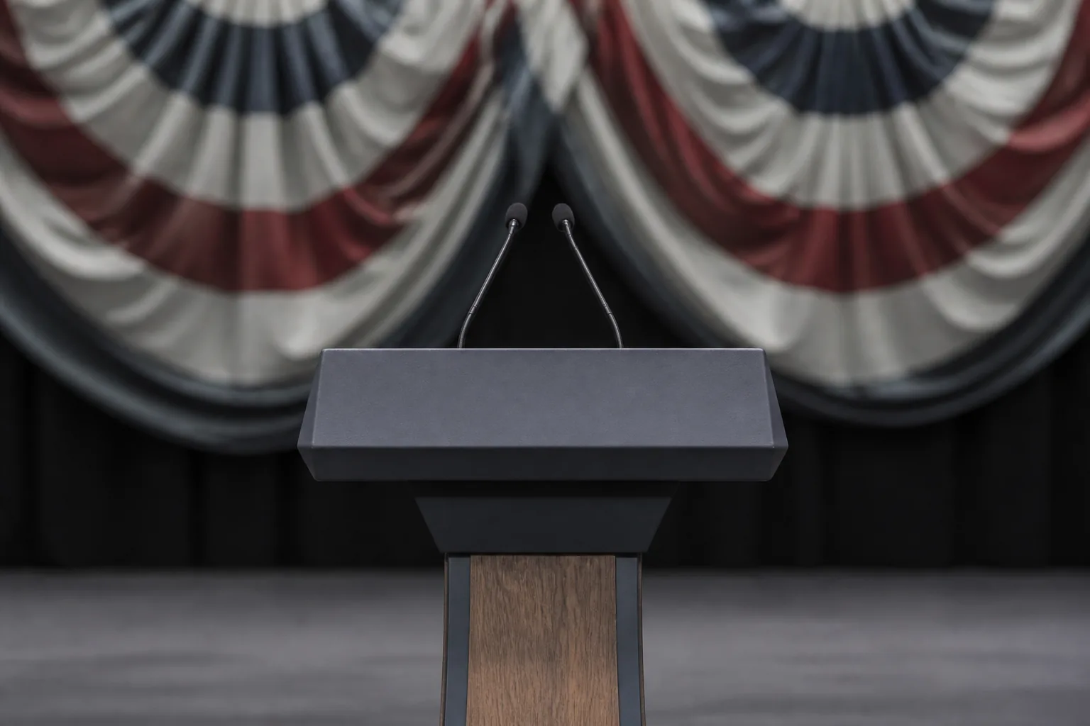 An empty lectern on a bare stage, drapes out of focus behind it under hard front lighting (AI-generated image)