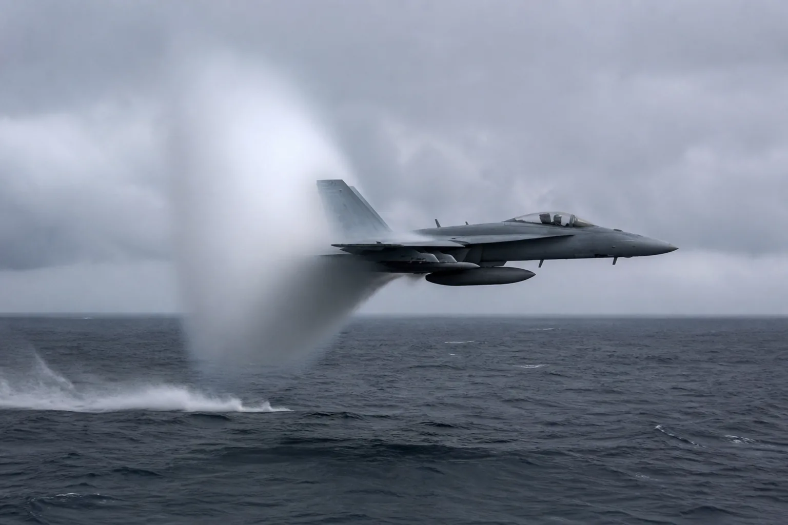 A grey fighter jet at very low level over open ocean, a sharp white cone of condensation around its rear fuselage (AI-generated image)