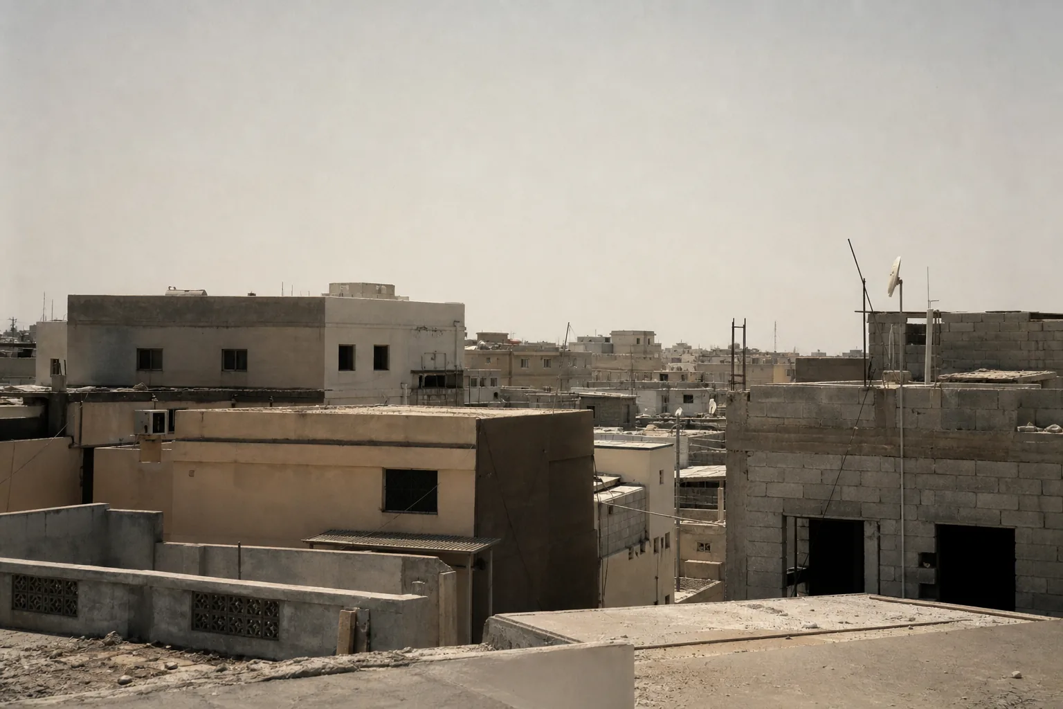 A dense low-rise urban block of flat-roofed concrete buildings seen from a rooftop (AI-generated image)