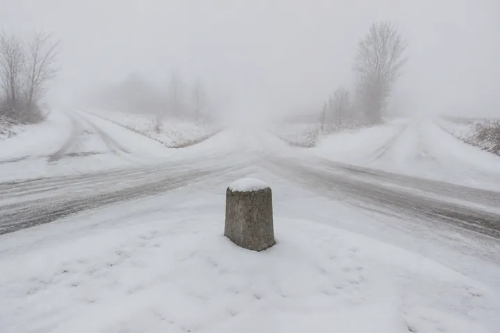 A crossroads in deep snow with a stone marker post and four empty roads leading away (AI-generated image)
