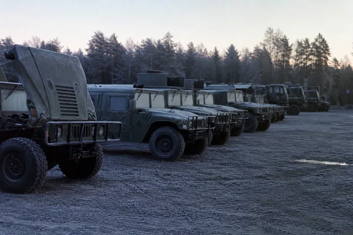 A battalion motor pool at dawn: rows of parked tactical vehicles under frost, one hood raised, nobody present (AI-generated image)