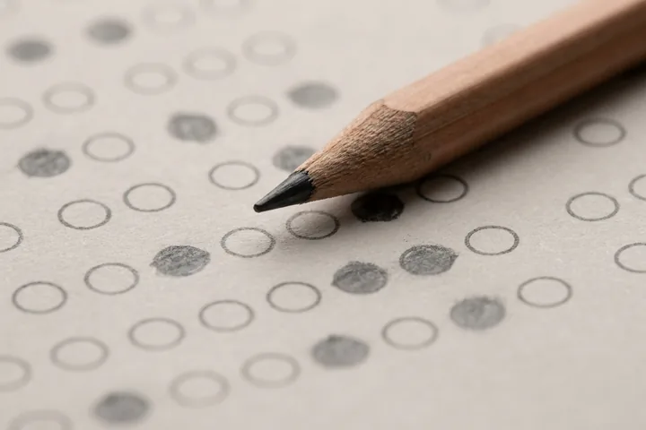 Sharpened wooden pencil tip resting on light textured paper with rows of filled and empty circles (AI-generated image)