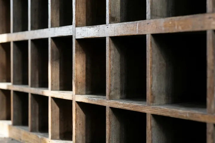 An array of empty, worn wooden cubbyholes forming a grid (AI-generated image)