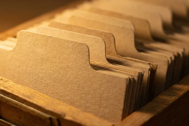 Textured brown paper index card dividers arranged upright in a wooden box (AI-generated image)