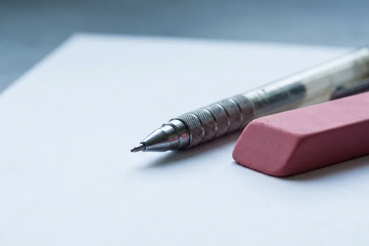 A silver mechanical pencil with a textured grip and a pink rectangular eraser resting on a white paper sheet in bright, soft light (AI-generated image)