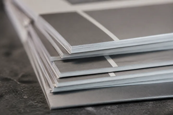 A stack of pamphlets fanned across a counter, their edges catching side light (AI-generated image)