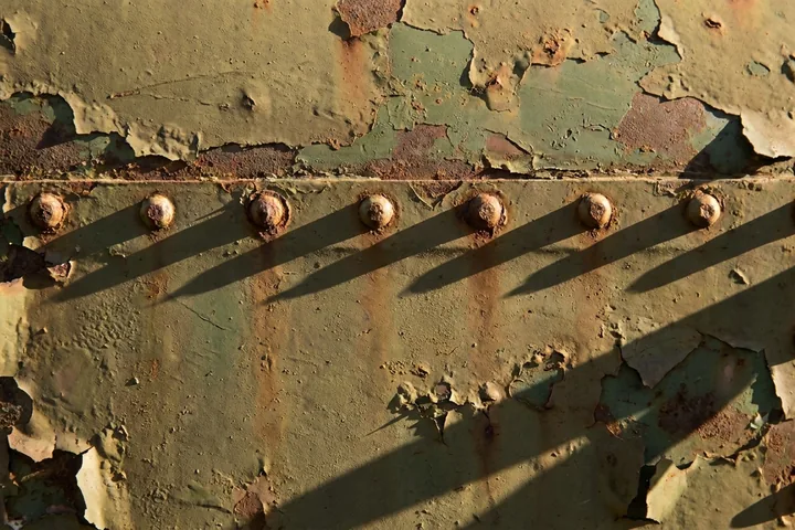 Severely rusted, peeling green metal panels joined by a horizontal riveted seam (AI-generated image)