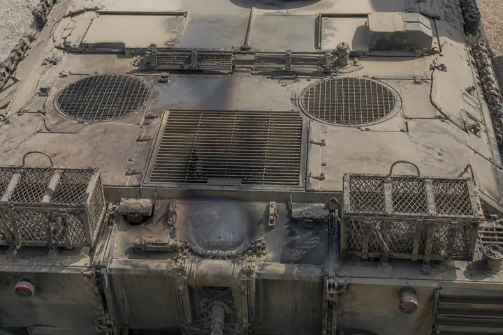 A tank's rear engine deck with exhaust grilles and stowage baskets, heat-discoloured metal (AI-generated image)