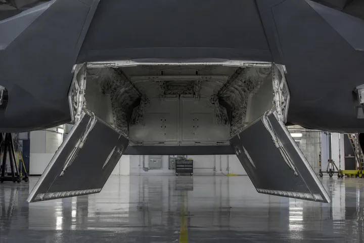 An open, empty weapons bay on the underside of a stealth aircraft in a hangar (AI-generated image)