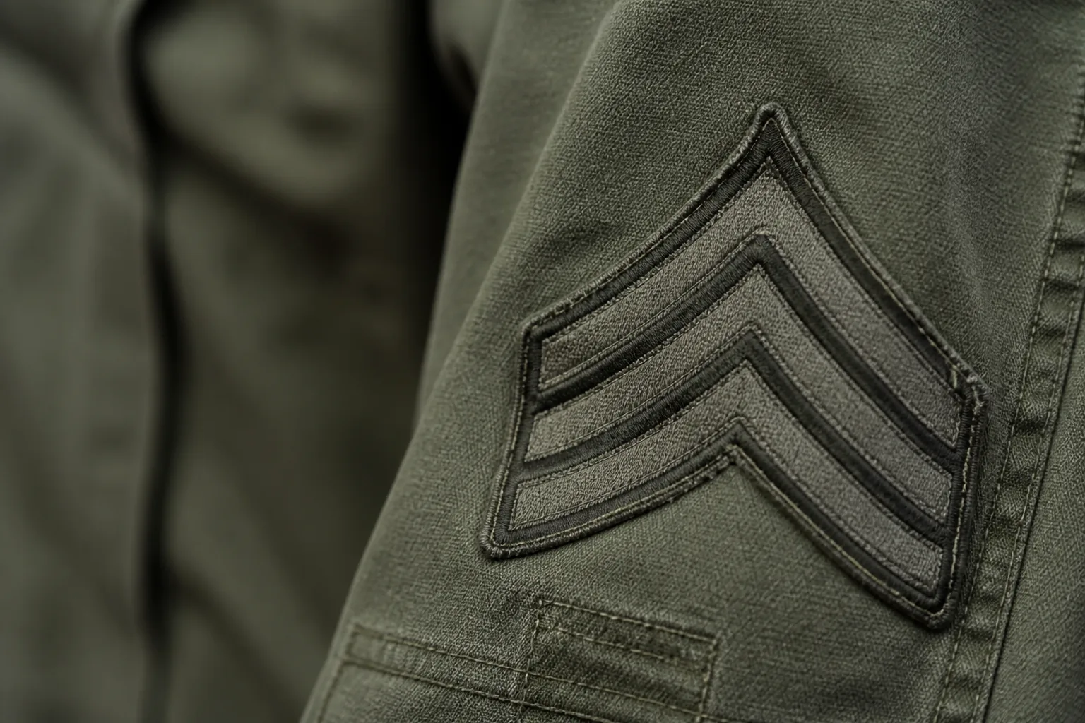 A sergeant's chevrons on a worn uniform sleeve, close and slightly angled in shallow focus (AI-generated image)