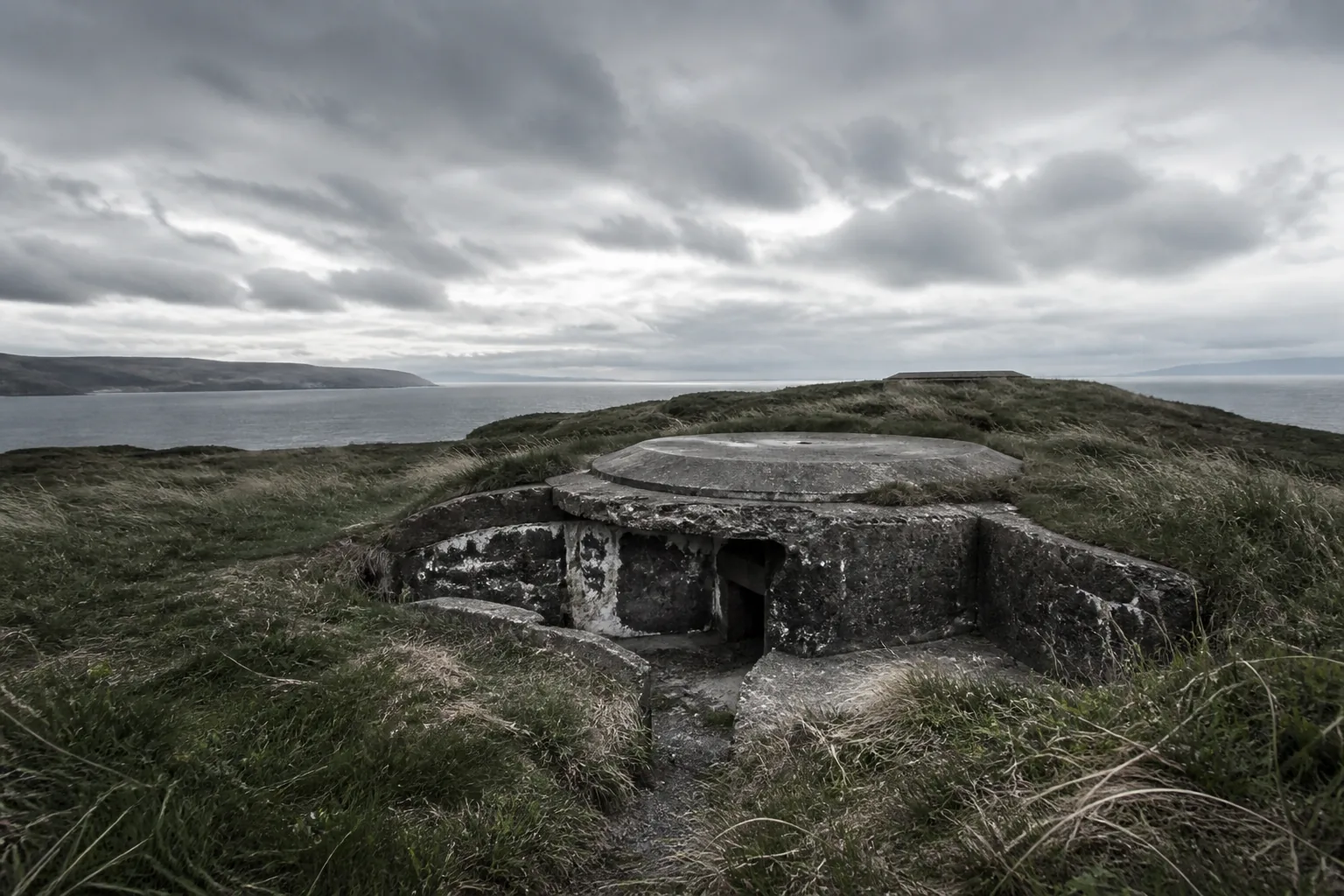 An old concrete coastal fortification overgrown with grass on a windswept headland (AI-generated image)