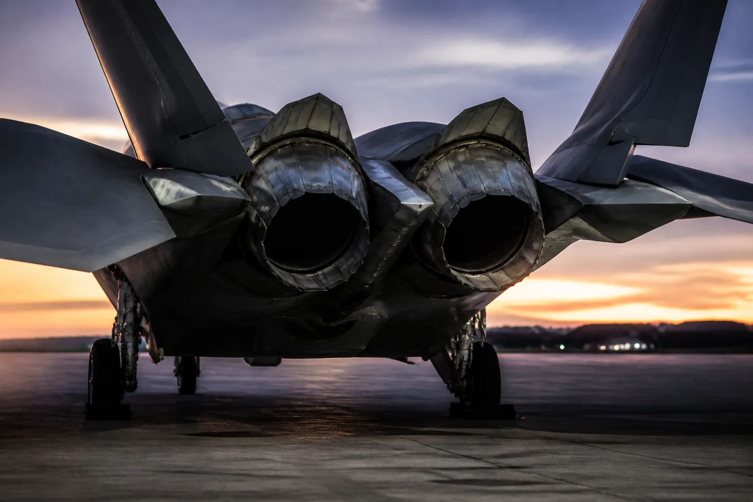 Twin thrust-vectoring engine nozzles and tailplanes of a stealth fighter seen from behind at dusk (AI-generated image)
