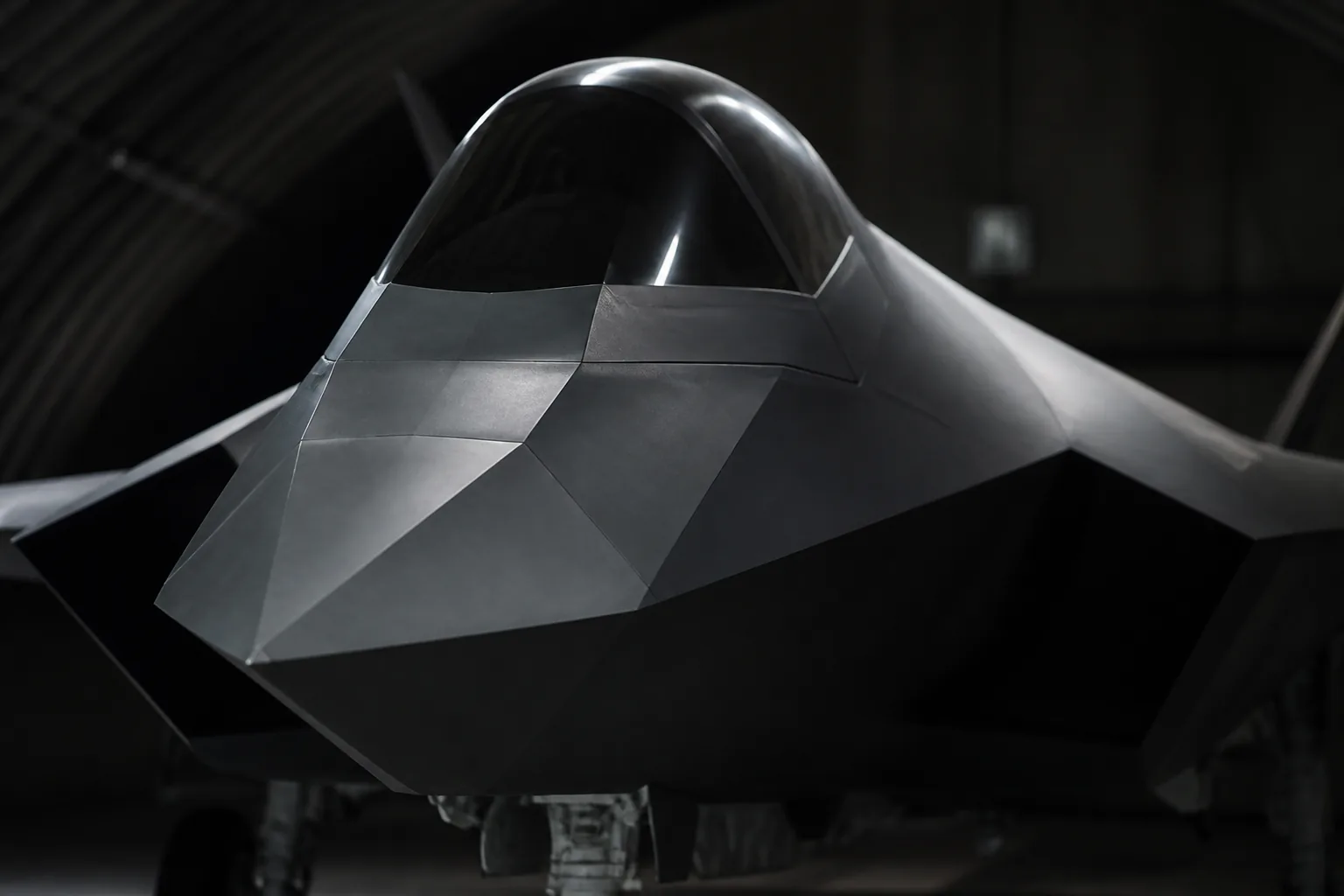 A stealth fighter's faceted nose and canopy inside a dim shelter, its edges catching a single light (AI-generated image)